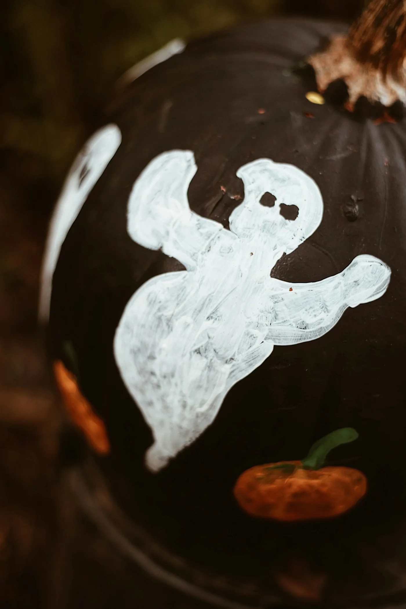 A pumpkin painted with a small ghost decoration